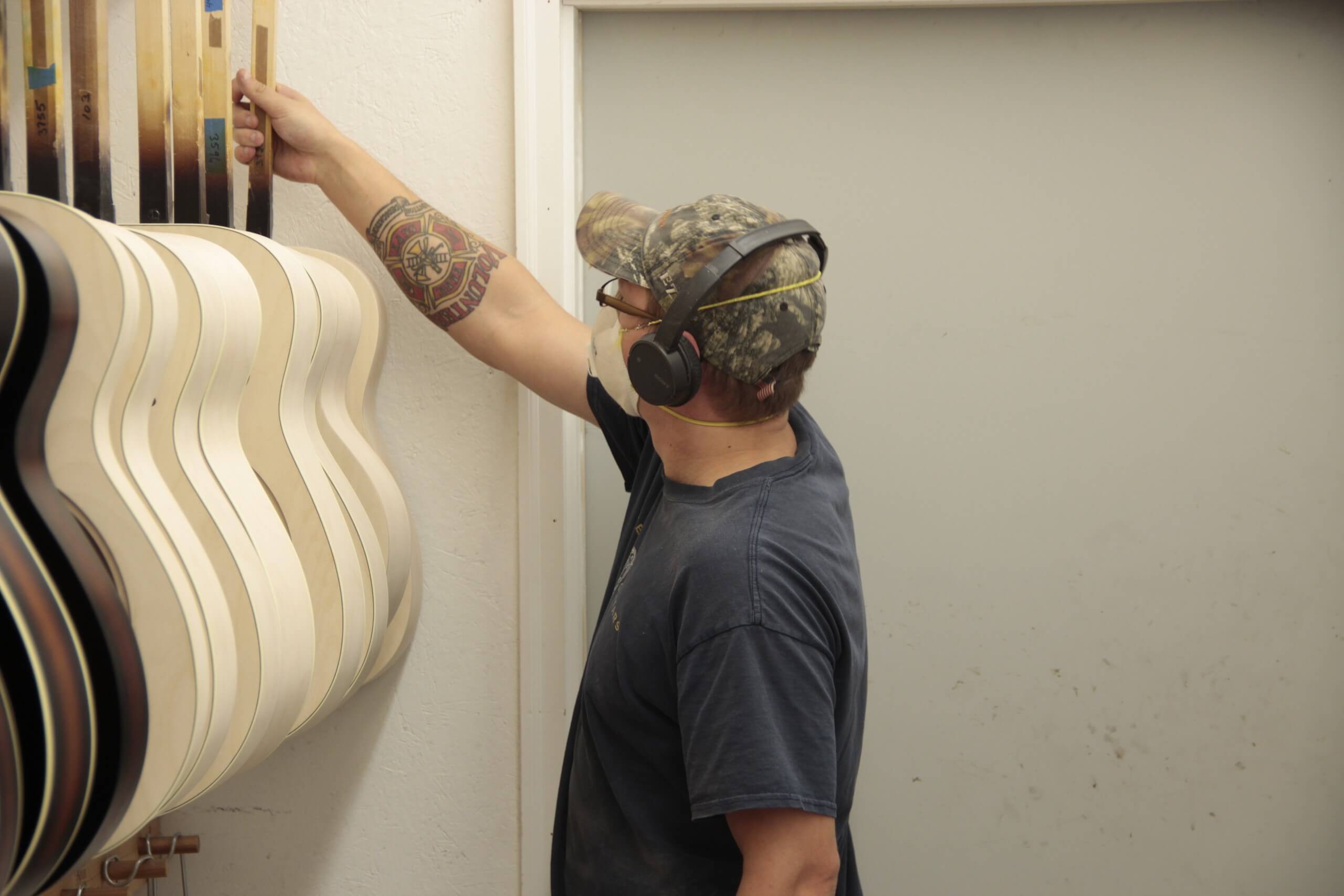 Person hanging up guitar bodies